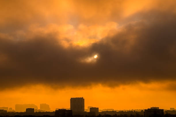 Morning over the city. Heavy clouds cover the sun in the dawn sky. Silhouettes of buildings in backlight
