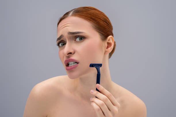 istock Young woman holding a shaver in hands and looking scared 2162652257