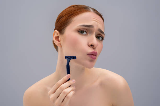 istock Young woman holding a shaver in hands and looking scared 2162652261