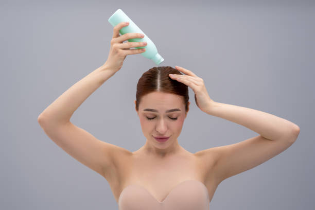 istock Young ginger woman using anti-dandruff shampoo while washing her hair 2162652273