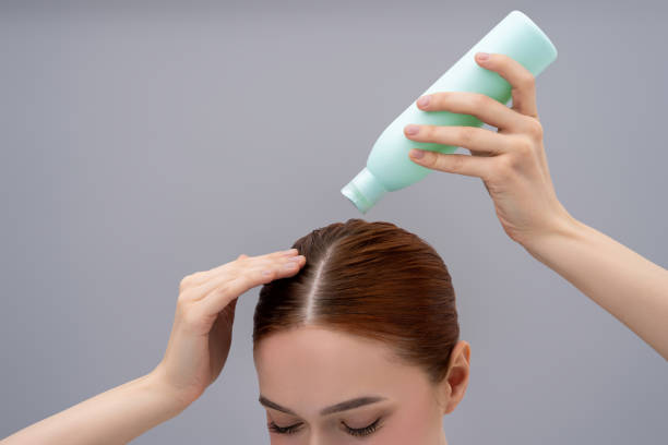 istock Young ginger woman using anti-dandruff shampoo while washing her hair 2162652292