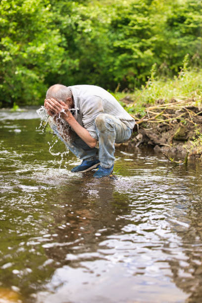 istock Homeless man washing himself on a river 2162654762