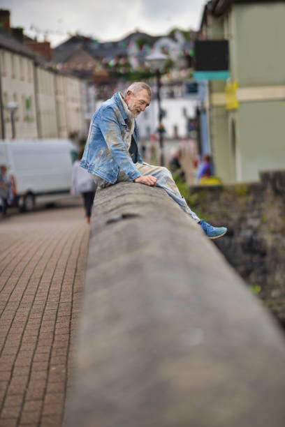 Dishevelled and dirty homeless man in a town centre. Posed by model.