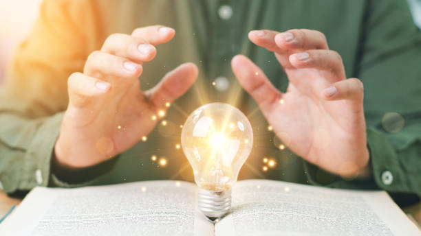 istock Hand touch light bulb or lamp on textbook thinking ideas or new ideas futuristic. Idea, Self learning, Studying concept. The idea of reading books, knowledge, and searching for new ideas. 2162661130