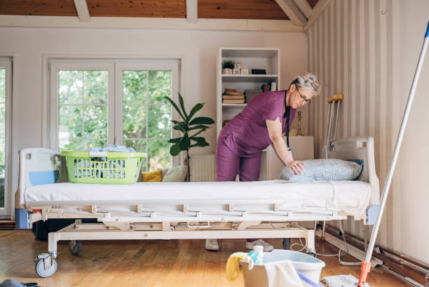 istock Nurse making bed in a bright room with large windows. 2162663959