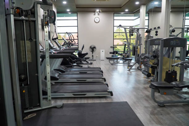 Background image of various exercise machines in workout hall of modern gym interior, copy space