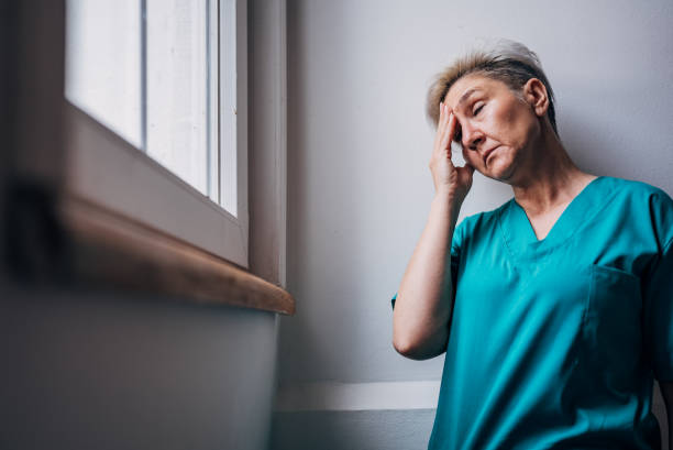 istock Nurse in scrubs with hand on head, feeling distressed. 2162664978