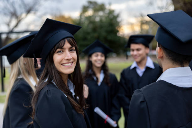 istock Happy student talking with a group of classmates on their graduation day 2162665265