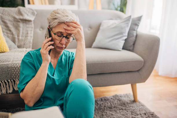 istock Nurse in teal scrubs looks distressed during call. 2162666665