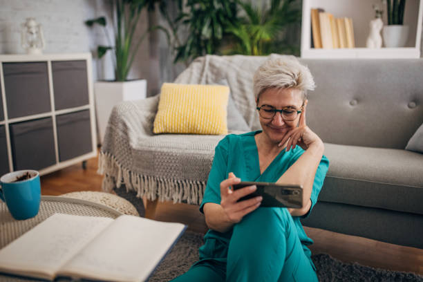 istock Content nurse sitting on floor watching phone in home 2162666816