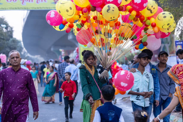 Ghaziabad, Uttar Pradesh, India - November 2023: Portrait of a young girlcarrying balloons with smile on his face during chhath puja to sell them. Childhood concept.