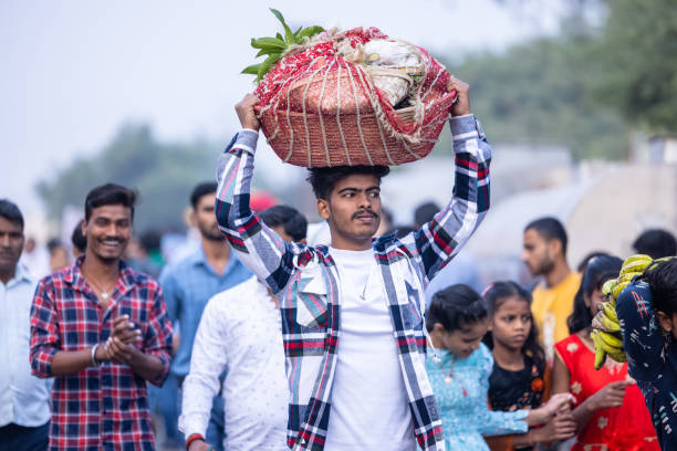 Ghaziabad, Uttar Pradesh, India - November 19 2023: Portrait of an hindu male devotee carrying the fruits and other ritual items over his head in a basket to perform the chhath puja near river bank.
