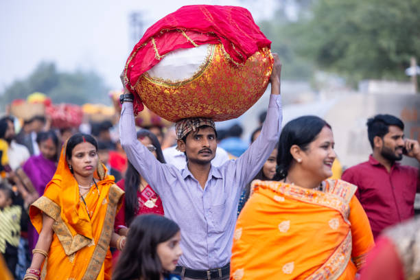 Ghaziabad, Uttar Pradesh, India - November 19 2023: Portrait of an hindu male devotee carrying the fruits and other ritual items over his head in a basket to perform the chhath puja near river bank.