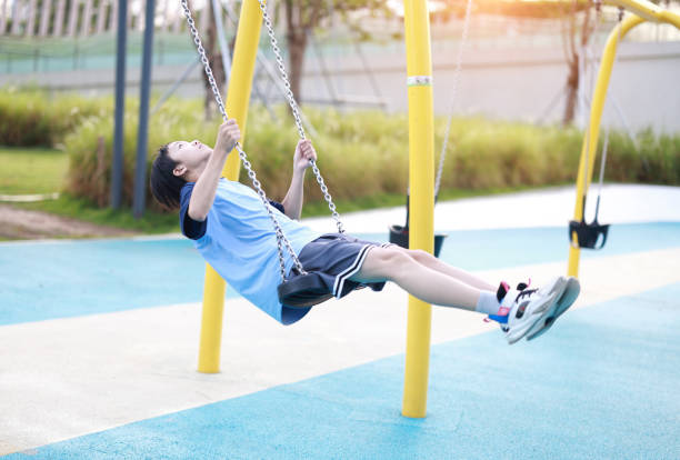 Boy has fun swinging in the city playground
