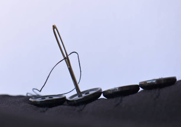 istock Sewing a button onto the arm cuff a men's business suit with a needle and thread 2162673804