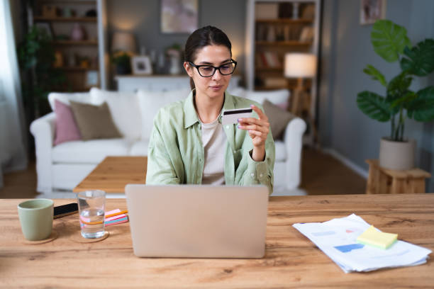 istock Young business woman using break from working in home office for paying home finances or online shopping with credit card and laptop computer. Confident female pay her online order. 2162675417