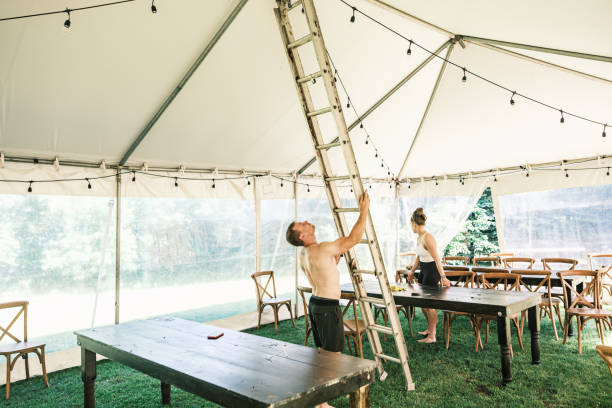 istock Young couple decorating lights inside wedding reception tent 2162676312