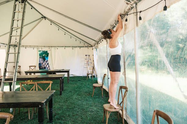 istock Young woman decorating lights inside wedding reception tent 2162676328