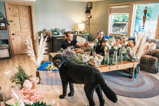 Young couple arranging their wedding flower decor. Dressed in casual clothes. Interior of cottage home in Muskoka, Ontario in Canada.