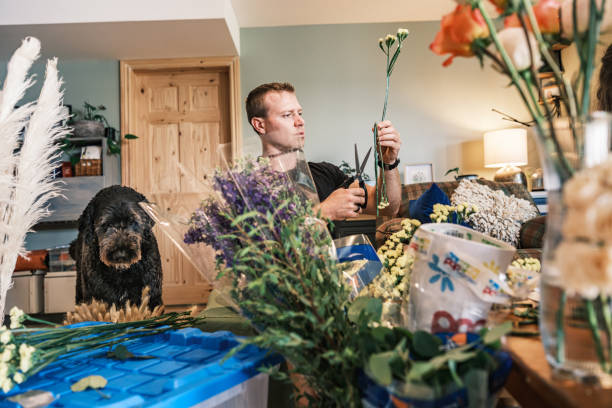 Young man arranging his wedding flower decor. He is dressed in casual clothes. Interior of cottage home in Muskoka, Ontario in Canada.