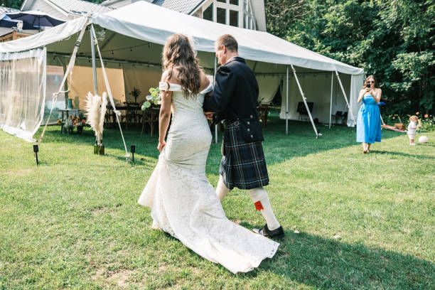 Bride and groom after outdoor wedding ceremony. Bride wearing wedding dress, Groom wearing traditional Scottish attire with kilt. Exterior of   cottage  country property in Muskoka, Ontario in Canada.