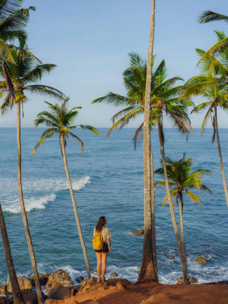 istock Woman looking at ocean standing among  palm trees grove 2162681764