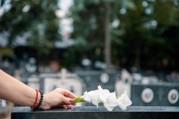 Female hand with white flower on the grave