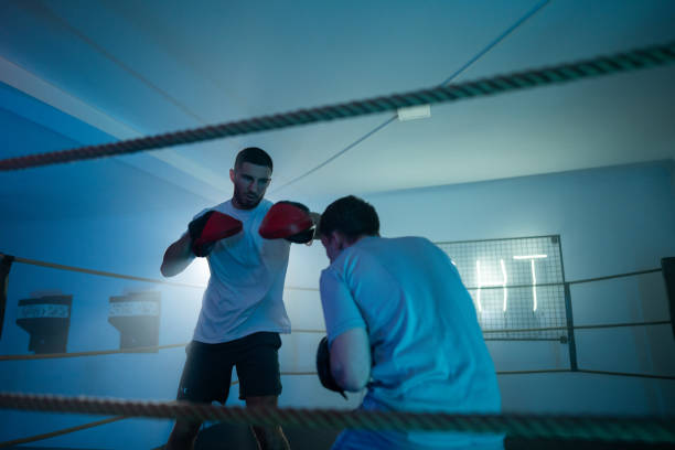 istock Young man at boxing training, he is sparring and practicing with his coach in boxing ring 2162685798