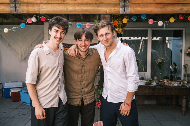 Three young men at the outdoor wedding party. Exterior of  cottage  country property on the lake in Muskoka, Ontario in Canada.