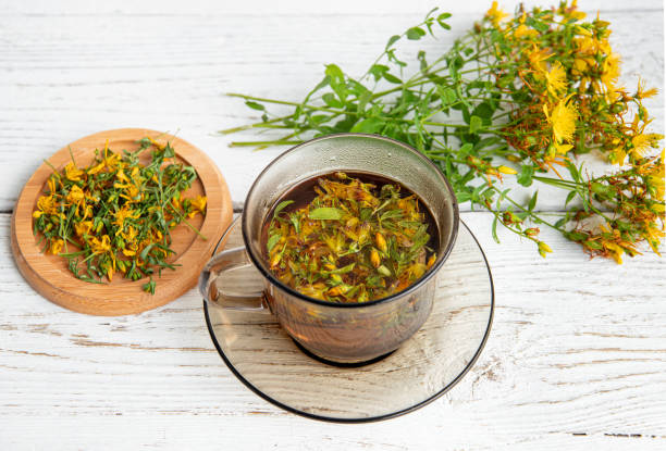 istock Hypericum perforatum commonly known as St John's wort, perforate St John's wort or common St John's wort herbal tea in glass on white wood board background. 2162690415