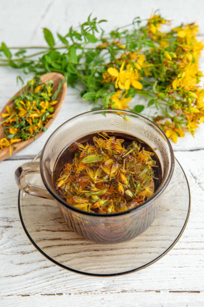 istock Hypericum perforatum commonly known as St John's wort, perforate St John's wort or common St John's wort herbal tea in glass on white wood board background. 2162690421