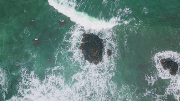 istock Dangerous waves splashing rocks top view. Stormy ocean water washing cliffs 2162697355