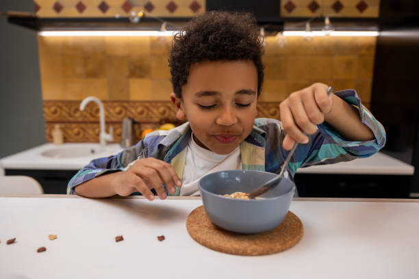 istock Dark-skinned boy sitting at the table and eating breakfast 2162697810