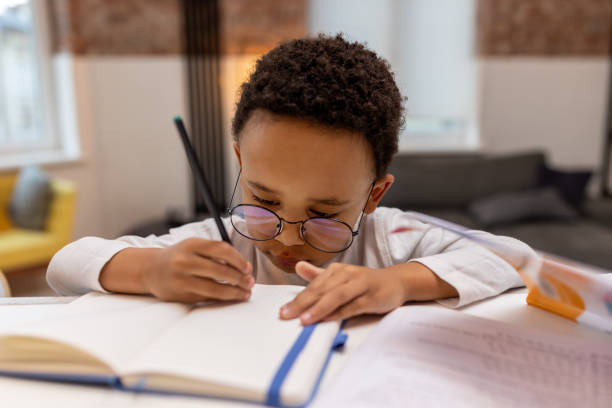 istock Dark-skinned cute boy doing lessons and looking involved 2162697826