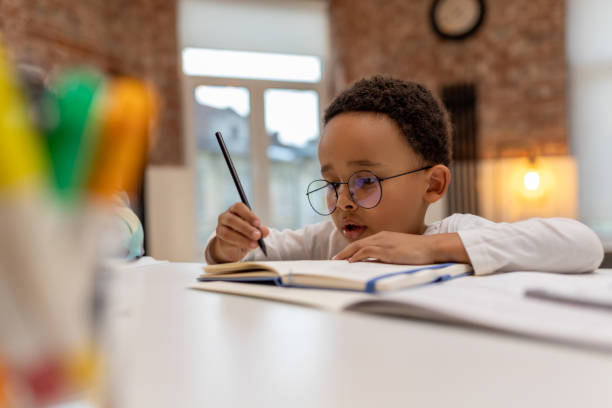istock African american boy doing lessons and writing something in a notebook 2162697844