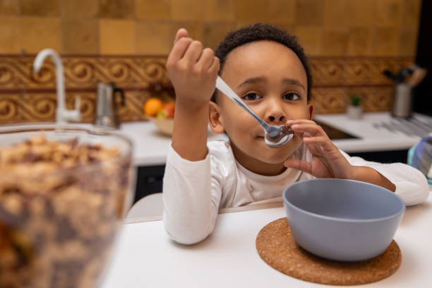 istock Dark-skinned boy sitting at the table and eating cereals 2162697864