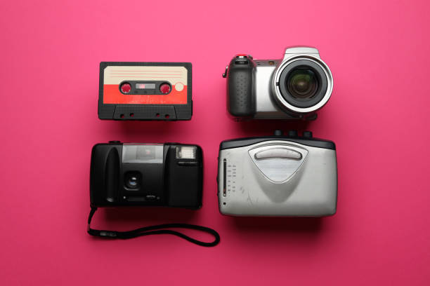 Three old cameras are displayed on a pink background