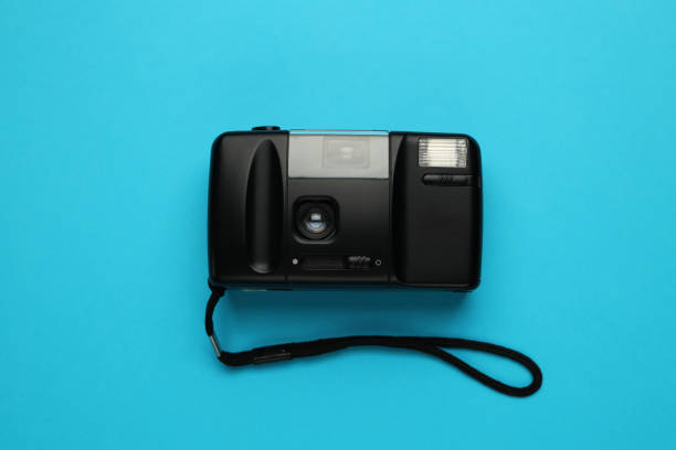 istock A black camera with a white lens sits on a blue background. The camera is turned off and has a black strap 2162706734