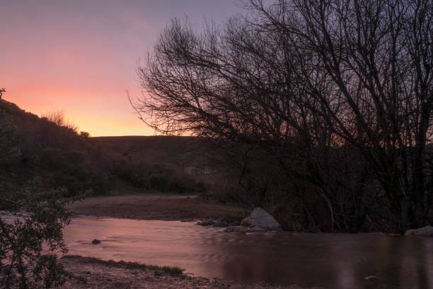istock A serene sunset landscape with a river and silhouetted trees in the foreground 2162707760