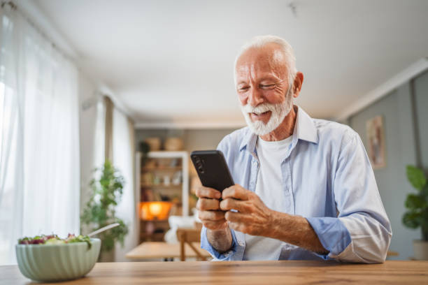 istock Senior man use a mobile phone while eat salad at home 2162709346