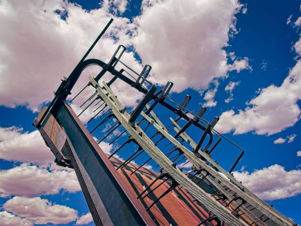 Old farm equipment and weathered buildings in arid field behind Hubbell trading post national historic site near Ganado Arizona.