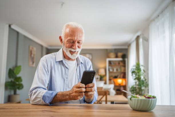 istock Senior man use a mobile phone while eat salad at home 2162709532