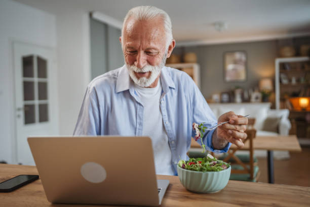 istock Senior caucasian man use laptop while eat salad at home 2162709575