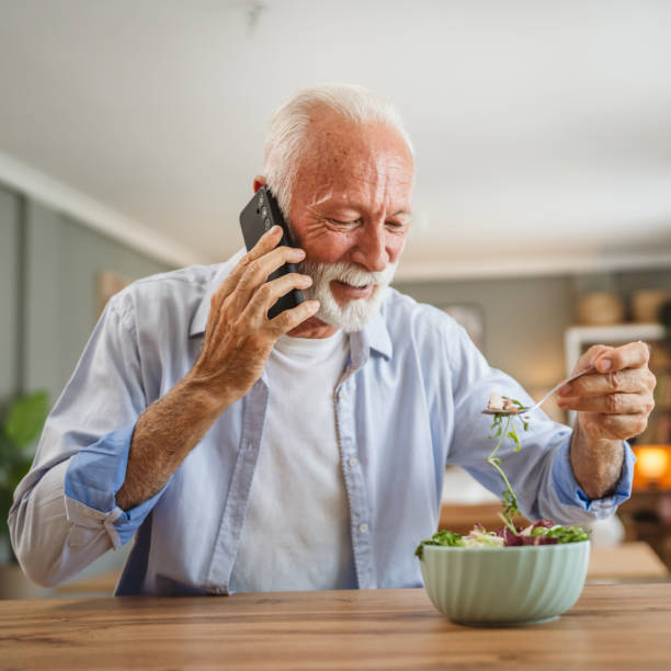 istock Senior man have a phone call while eat salad at home 2162709984