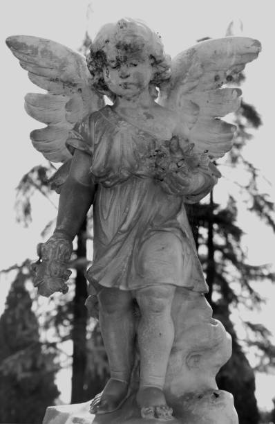 Stone angel, looking into infinity. Represents the escort of the soul to eternal life. Late afternoon with blue sky and crescent moon. Necrotourism.