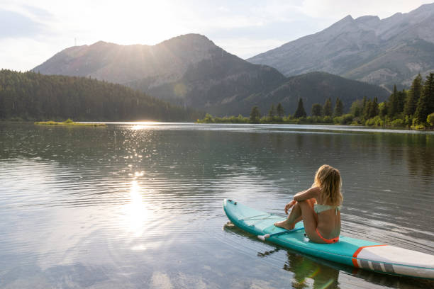istock Young woman relaxes on SUP board on lake 2162717885