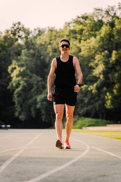istock Professional athlete in training clothes smiling while walking on the track 2162720073