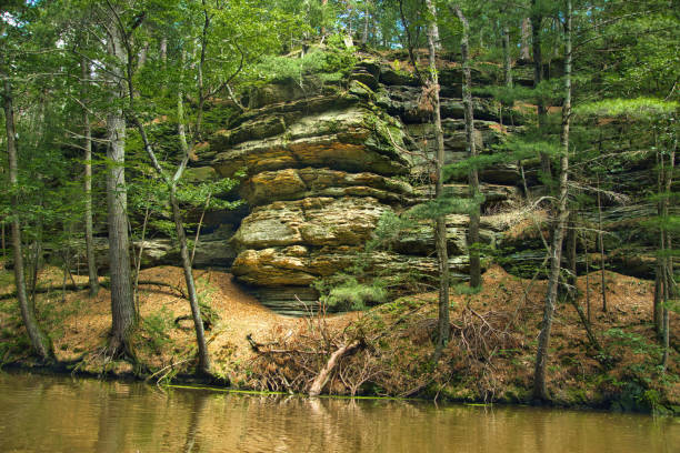 Summer’s day landscape of sandstone cliffs and a lush green forest along the banks of Mirror Lake, near Baraboo, Wisconsin.