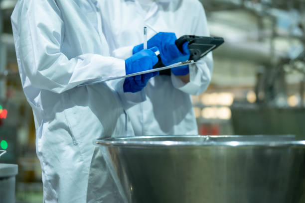 istock Two female scientists wearing protective equipment and use a tablet and clipboard to verify the correctness of the ingredients in the beverage mixing tank. 2162728321