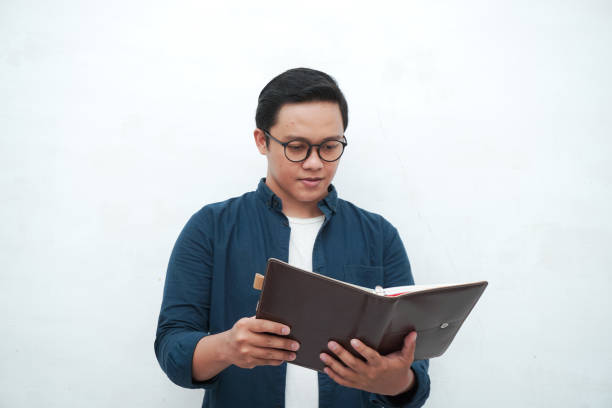 istock Young Asian man holding books while thinking and concentrating. 2162737911
